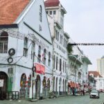 A street view of white Dutch colonial buildings with arched windows and red tiled roofs in the Kota Tua district of Jakarta.