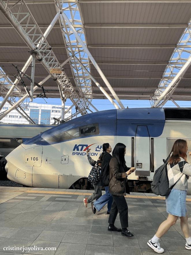 KTX-Sancheon high-speed train in South Korea with sleek blue and white design, passengers walking on the platform, and modern station canopy overhead.