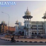 Historical Indo-Saracenic building in Kuala Lumpur, Malaysia, with ornate domes, arched windows, and decorative columns, set against modern city buildings