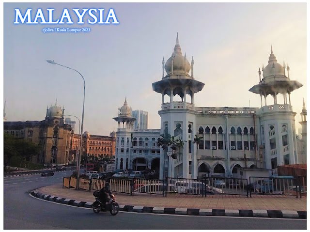 Historical Indo-Saracenic building in Kuala Lumpur, Malaysia, with ornate domes, arched windows, and decorative columns, set against modern city buildings