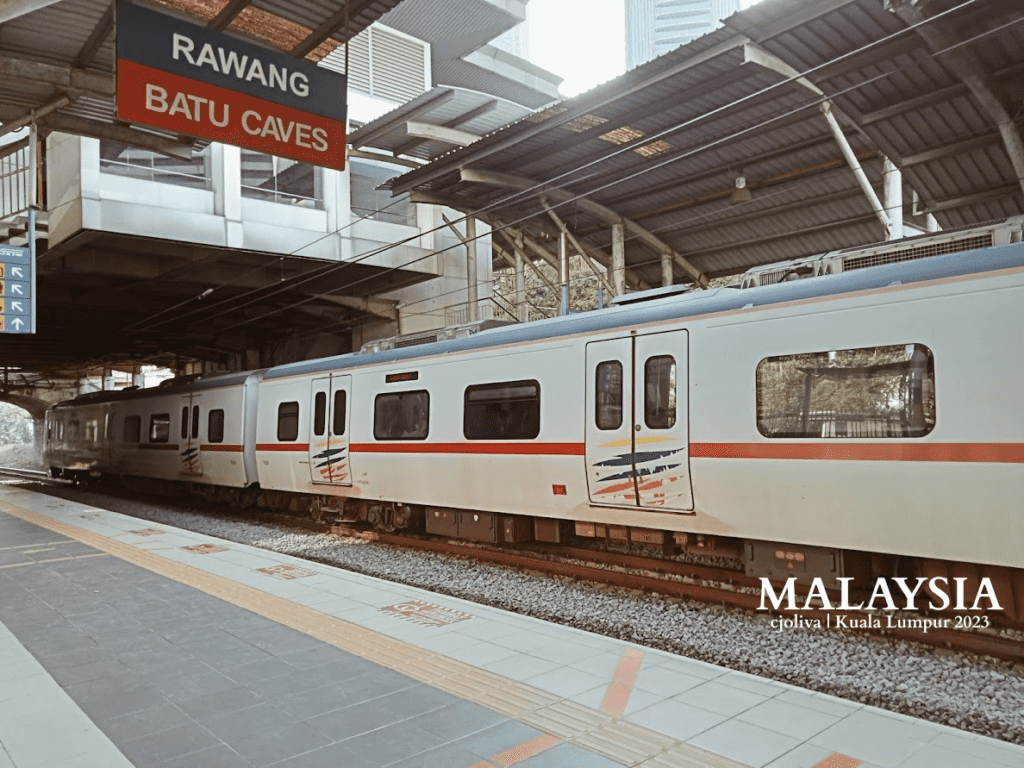 Commuter train at Kuala Lumpur station in Malaysia, with signage for Rawang and Batu Caves, modern design, and covered platform.