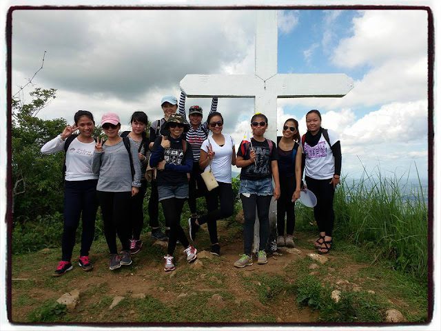 Group of hikers posing at Mt. Manabu summit cross during Freedom Climb in Batangas