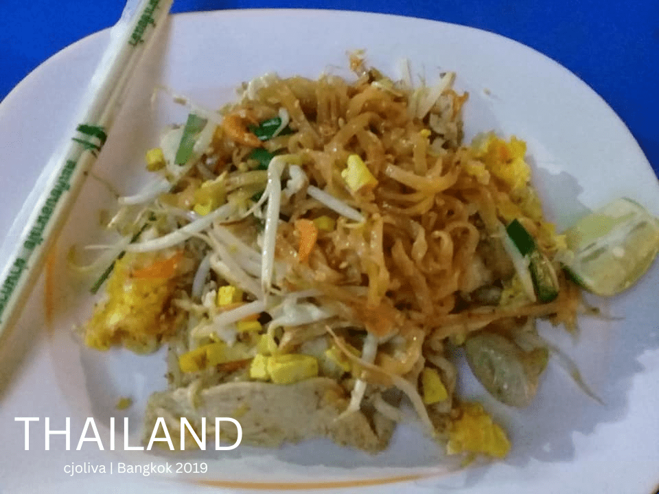 A close-up plate of authentic Thai Pad Thai with lime and sprouts on a blue table in Bangkok.