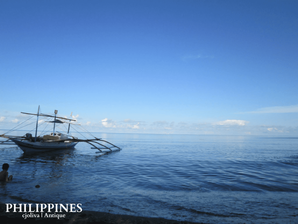 Traditional Filipino bangka boat floating on calm blue waters in Antique, Philippines