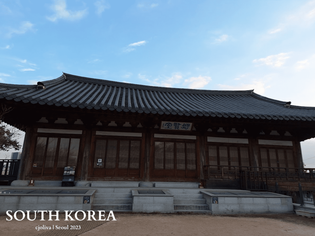 The traditional Korean building Ho Hyeon Dang in Seoul with a tiled roof, wooden lattice doors, and a stone platform under a clear sky.