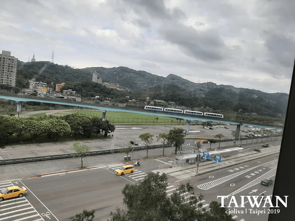 Taipei urban landscape with elevated train, taxis, and mountain backdrop in 2019