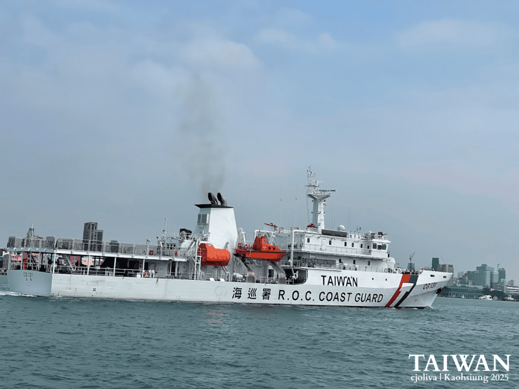 Taiwan Coast Guard ship CG131 with lifeboats and exhaust smoke sailing near Kaohsiung cityscape