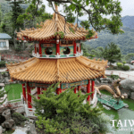 Zhinan Temple pavilion in Taipei with a golden roof, red columns, and a dragon pond surrounded by greenery