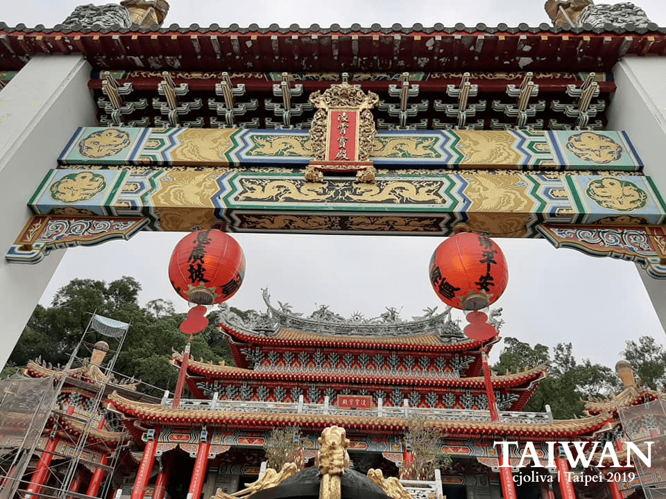 Zhinan Temple entrance gate in Taipei with ornate carvings, red lanterns, and colorful roof patterns
