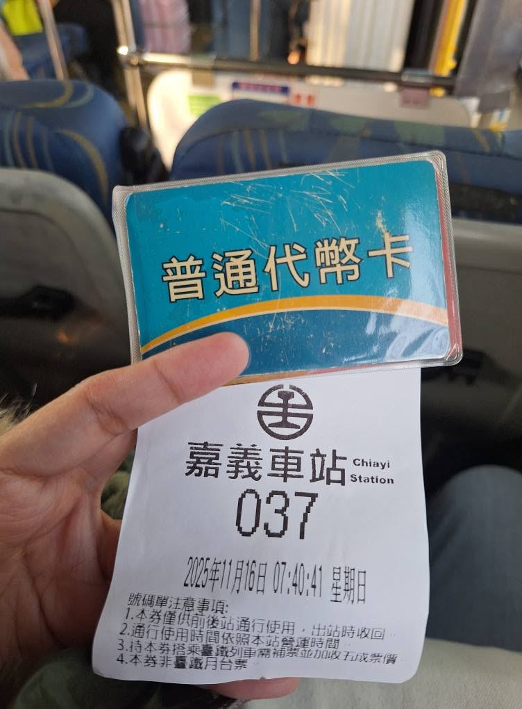 Traveler holding a blue bus magnetic card and a Chiayi Station ticket while seated on a bus in Taiwan.