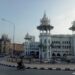 Kuala Lumpur Railway Station with white Mughal-style domes, ornate arches, and a motorcyclist riding along the curved road in front.