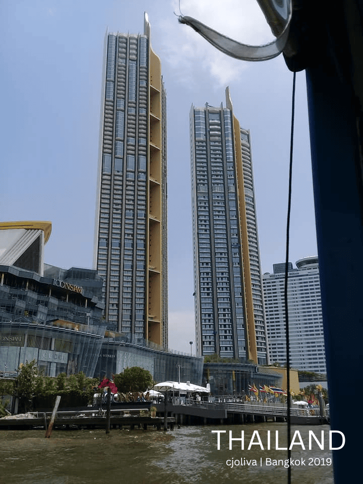 Two tall IconSiam towers with glass and gold accents next to riverside shopping mall in Bangkok, Thailand