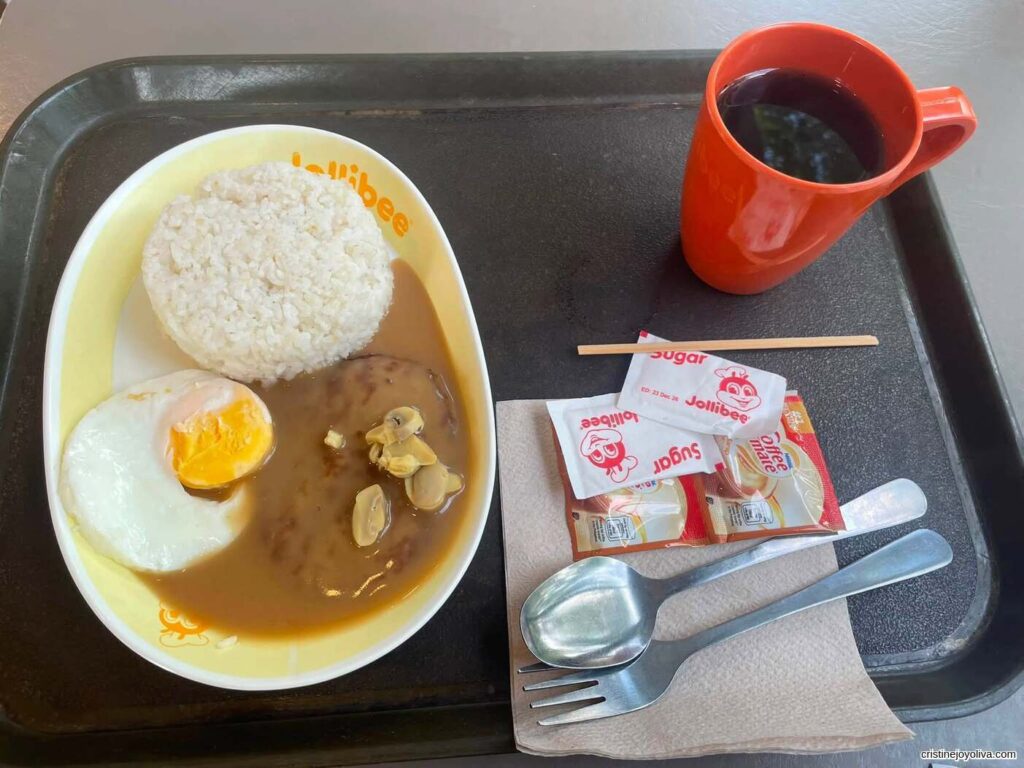 Jollibee breakfast plate with rice, fried egg, burger steak with gravy, and a cup of coffee