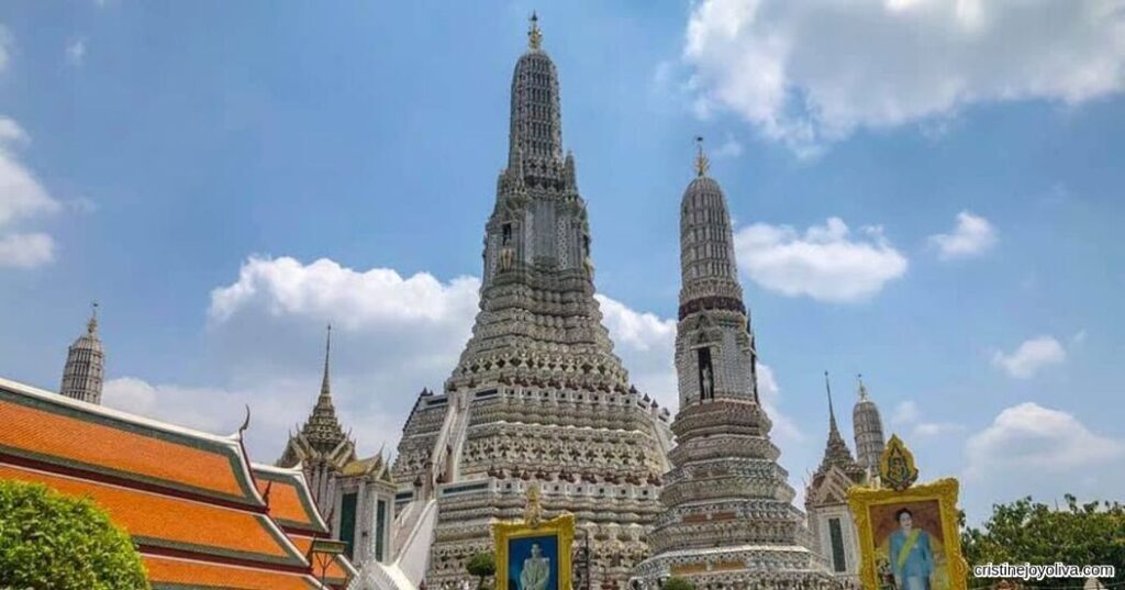 Wat Arun temple with detailed spires standing tall under blue sky in Bangkok, Thailand
