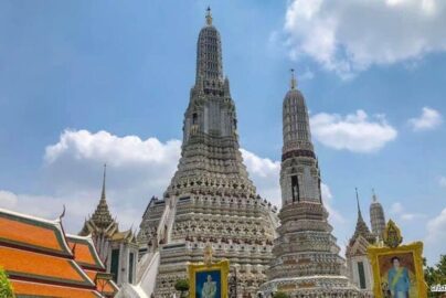 Wat Arun temple with detailed spires standing tall under blue sky in Bangkok, Thailand