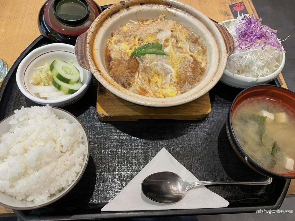 A hot Japanese katsudon set meal served with steamed rice, miso soup, pickled vegetables, and shredded cabbage in Plaza Indonesia.