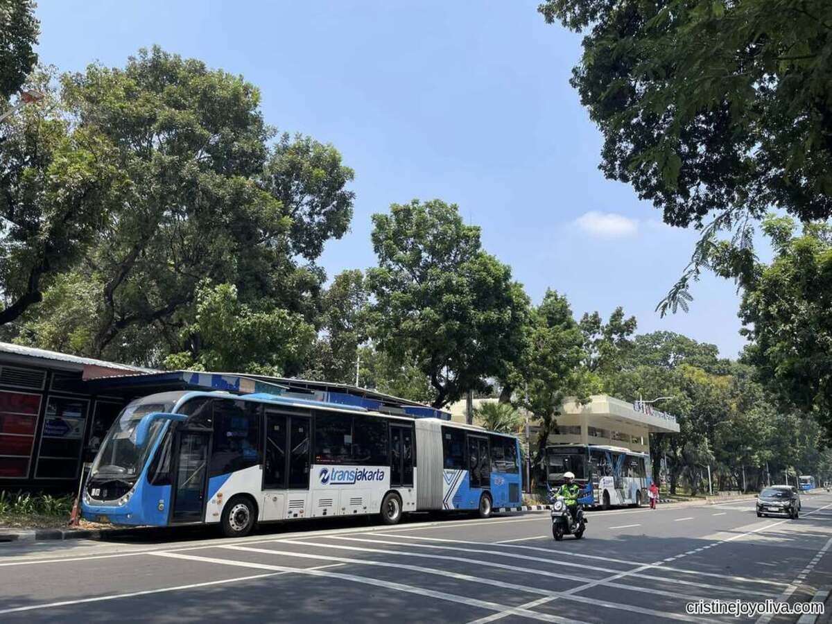 The Blue TransJakarta articulated bus stopped at Monumen Nasional station for solo backpacking in Jakarta, Indonesia.