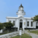 The historic Kaohsiung Lighthouse on Cijin Island, a stunning white lighthouse and museum against a clear blue sky, is a popular landmark for visitors in Kaohsiung, Taiwan.