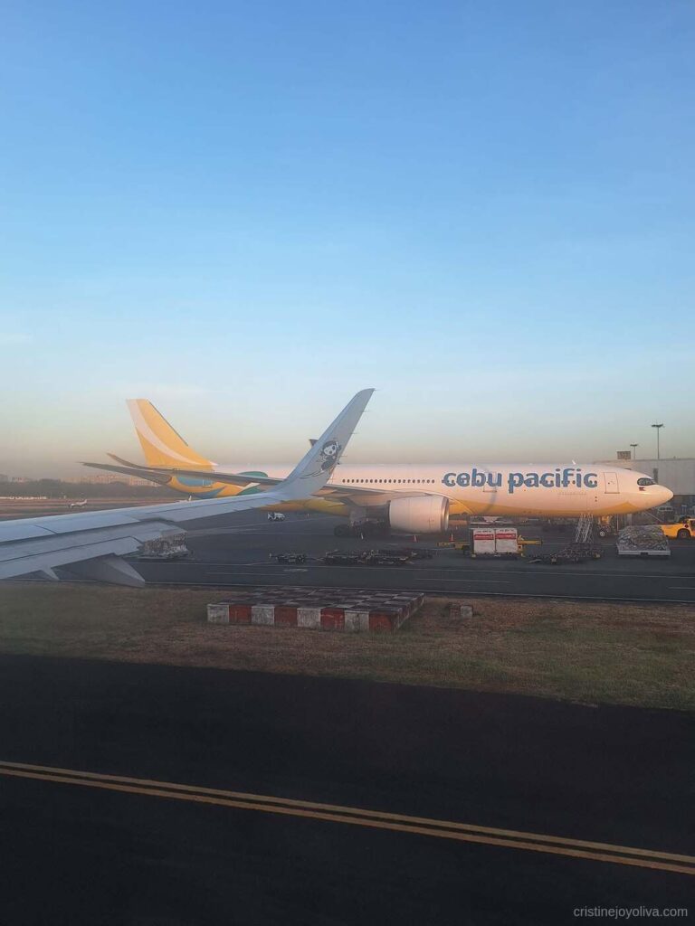 View from the airplane window of a Cebu Pacific aircraft parked on the tarmac at NAIA Manila Airport before departure to Singapore