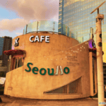 A cylindrical beige café building with green Seoullo signage bathed in warm sunset light along the Seoullo 7017 elevated skygarden in Seoul, South Korea.