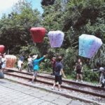 Travelers on the Pingxi Line itinerary release colorful sky lanterns inscribed with handwritten wishes over the railway tracks in Pingxi, Taiwan.