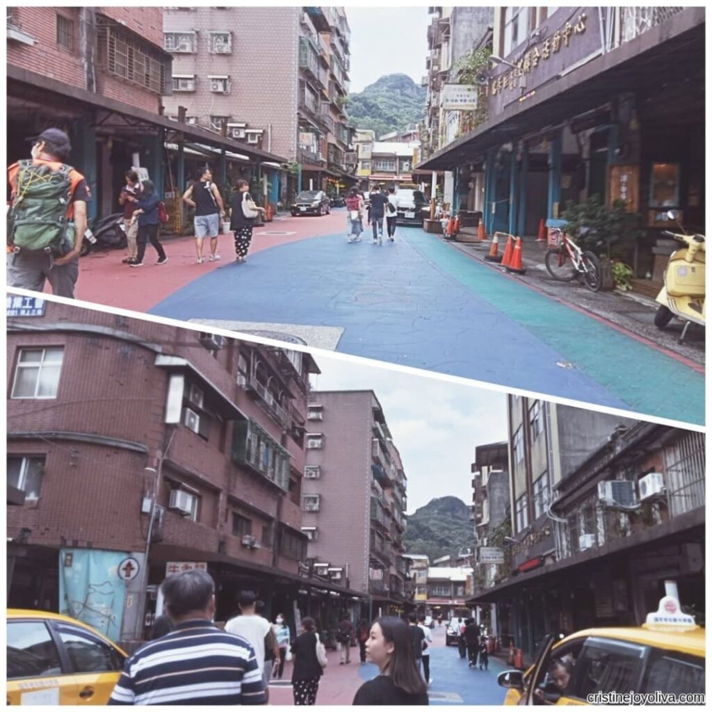 Ruifang Old Street, Taiwan, with a colorful crosswalk, shopfronts, taxis, and mountains in the background.