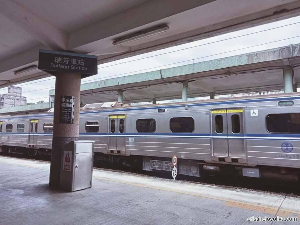 The Ruifang Station sign and Pingxi Line waiting zone platform in Taiwan, with a train parked alongside.