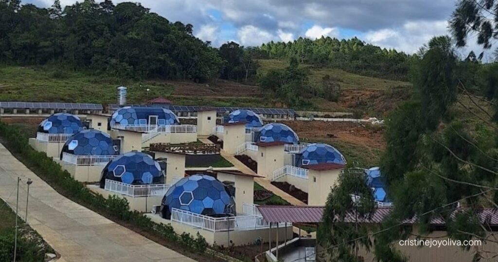 Futuristic blue geodesic dome cabins arranged along a hillside resort property with mountain greenery and a cloudy blue sky at Aningalan Mountain Resort.