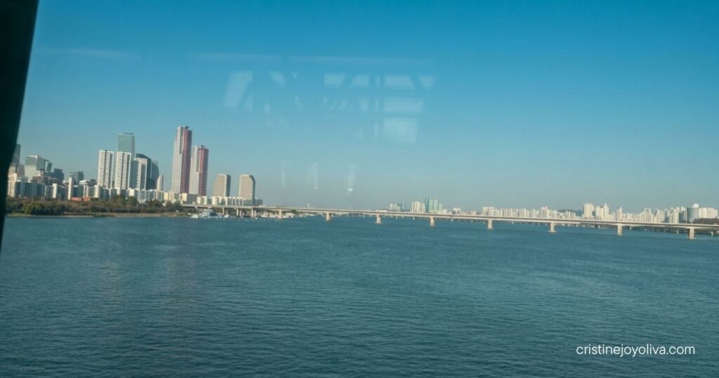 River and city skyline with a long bridge, seen from a KTX window on the Busan to Seoul ride