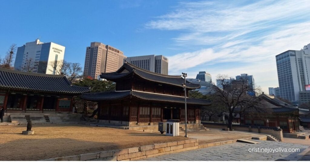 Traditional hanok hall at Deoksugung Palace with modern Seoul skyscrapers in the background