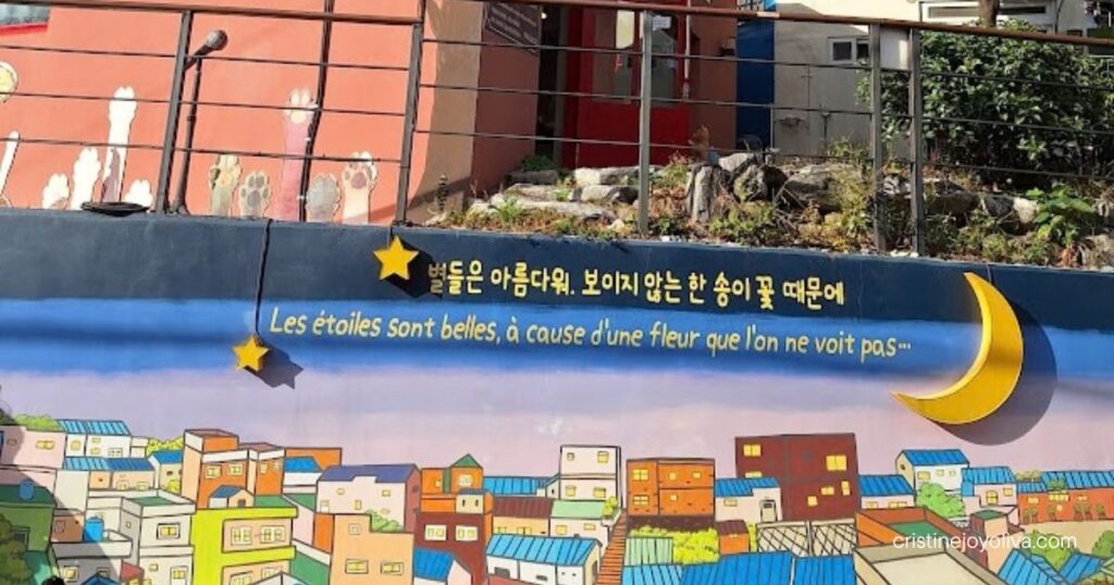The Little Prince quote mural with village artwork in Gamcheon Culture Village.