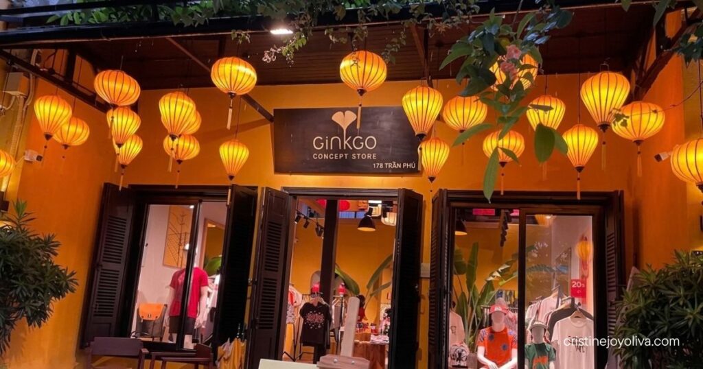A yellow boutique storefront illuminated by glowing orange silk lanterns at night on Tran Phu street in Hoi An.