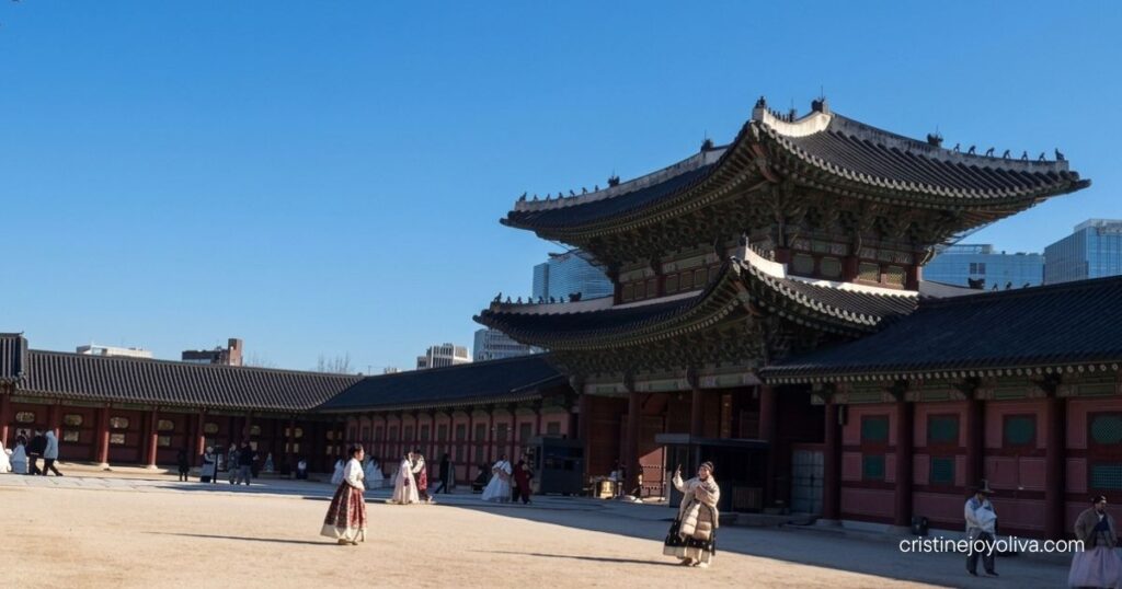 Visitors wearing traditional Hanbok pose for photos in the spacious inner courtyard of Gyeongbokgung Palace in Seoul.
