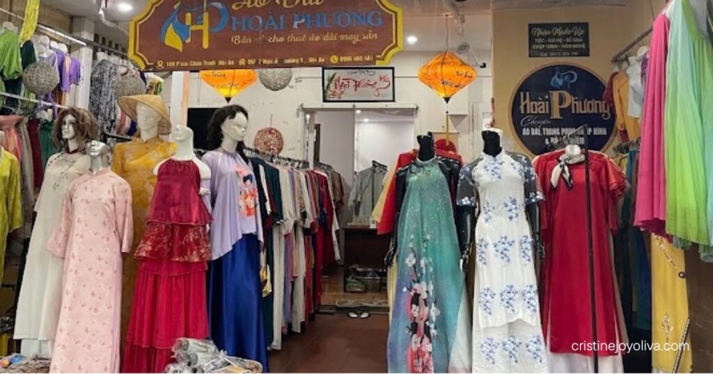Mannequins displaying traditional Vietnamese Áo Dài dresses outside the Hoài Phương shop on a street in Hoi An.