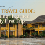 A detailed view of the weathered yellow-walled French colonial administration building in Hoi An, Vietnam, on a rainy day with wet pavement, featuring the overlay text 'Hoi An Travel Guide.'