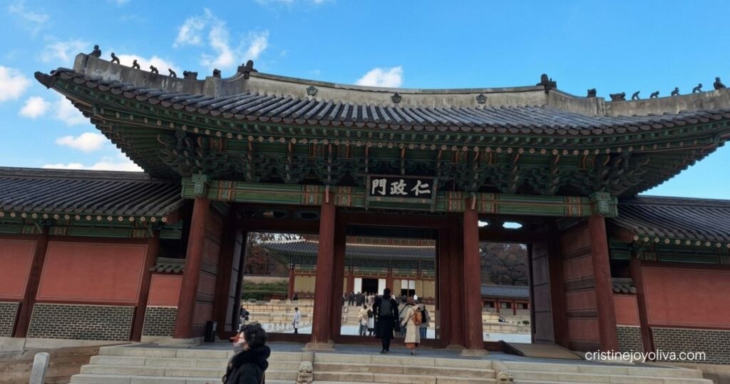 Historical architecture of the Injeongmun Gate entrance at Changdeokgung Palace in Seoul under a blue sky.