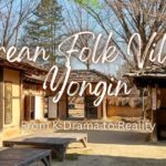 Traditional courtyard with wooden benches and hanok buildings at Korean Folk Village Yongin, framed by a wooden gate.