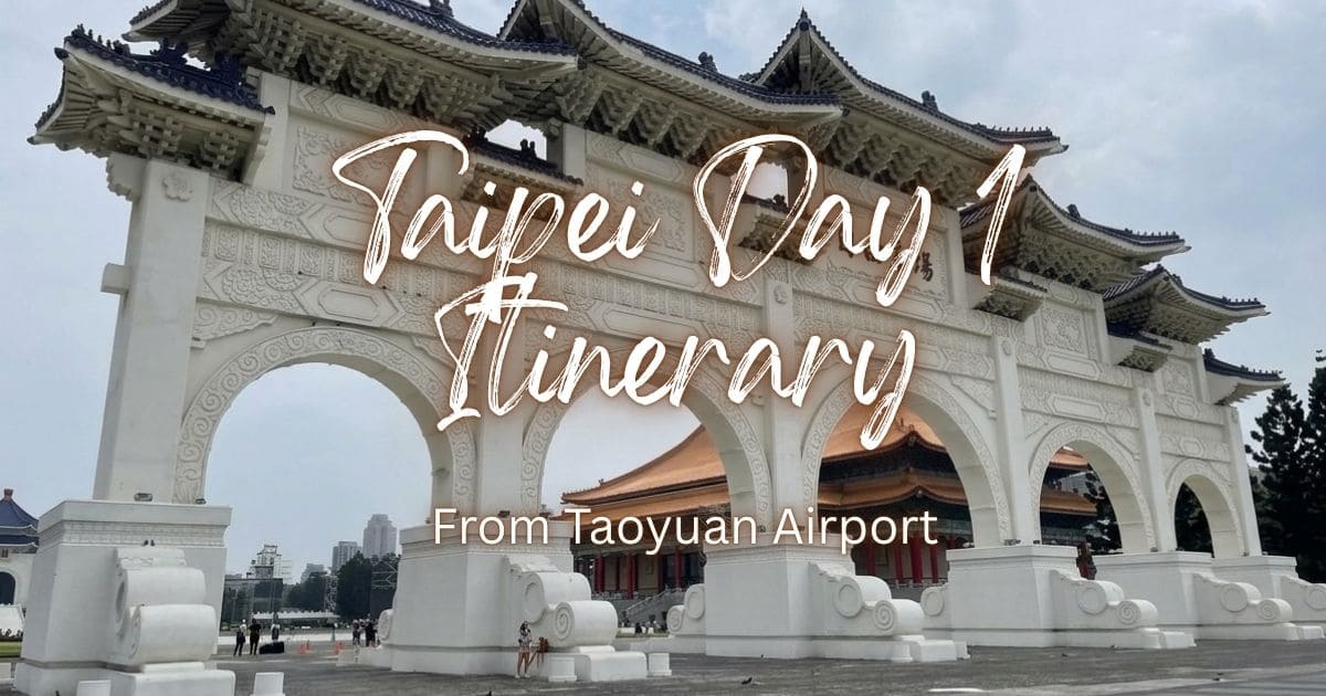 The grand white entrance arch of Liberty Square with blue tiled roofs in Taipei under an overcast sky.