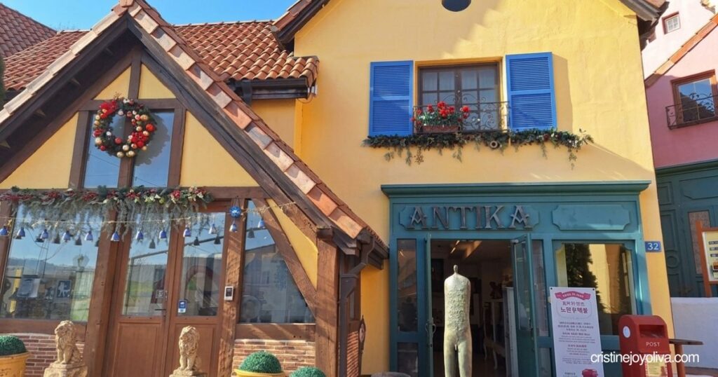 Yellow French-style building with blue shutters and an “ANTIKA” storefront sign in Petite France, featured in this Petite France & Italian Village Guide.