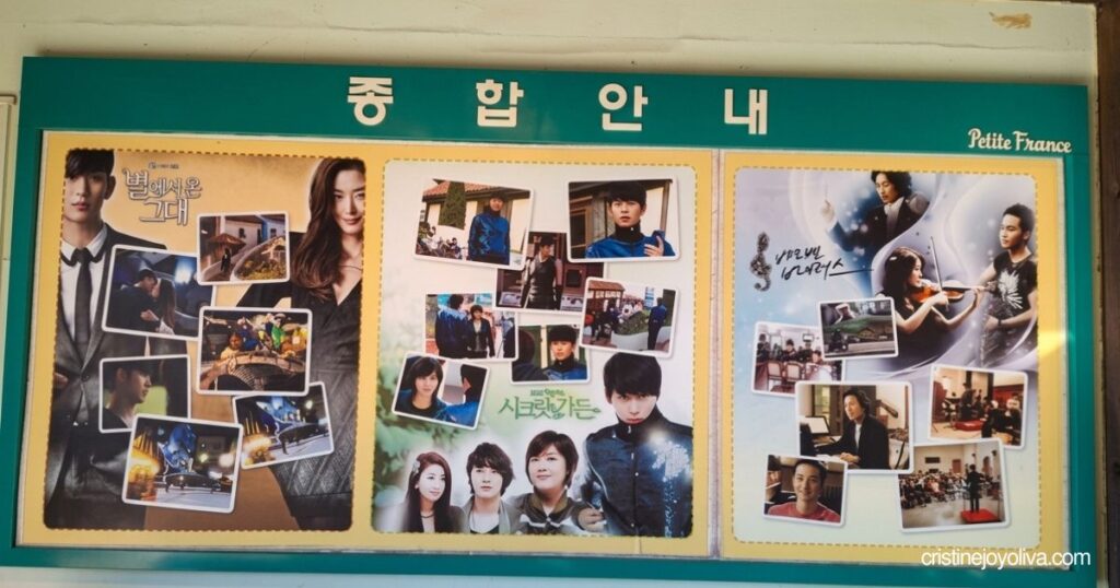 Information board displaying photos and posters of Korean dramas filmed at Petite France, including My Love from the Star and Secret Garden, featured in this Petite France & Italian Village Guide.