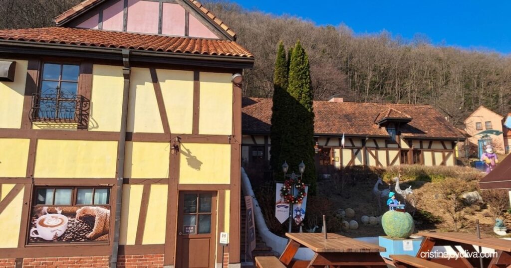 Wooden picnic tables sit on an outdoor patio in front of half-timbered European buildings in Petite France