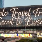 Solo travel from Seoul to Busan: Busan Station in the rain with umbrellas and a colorful LED screen