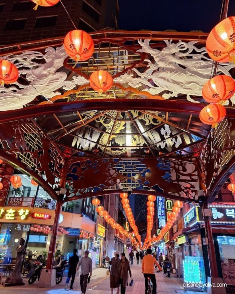 A decorative red lantern archway lit up at night along Texas Street in Busan during a one-day itinerary.