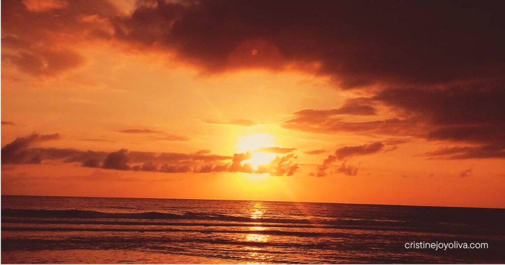Fiery orange golden sunset glowing over gentle ocean waves along the coastal waters of Antique, Philippines.