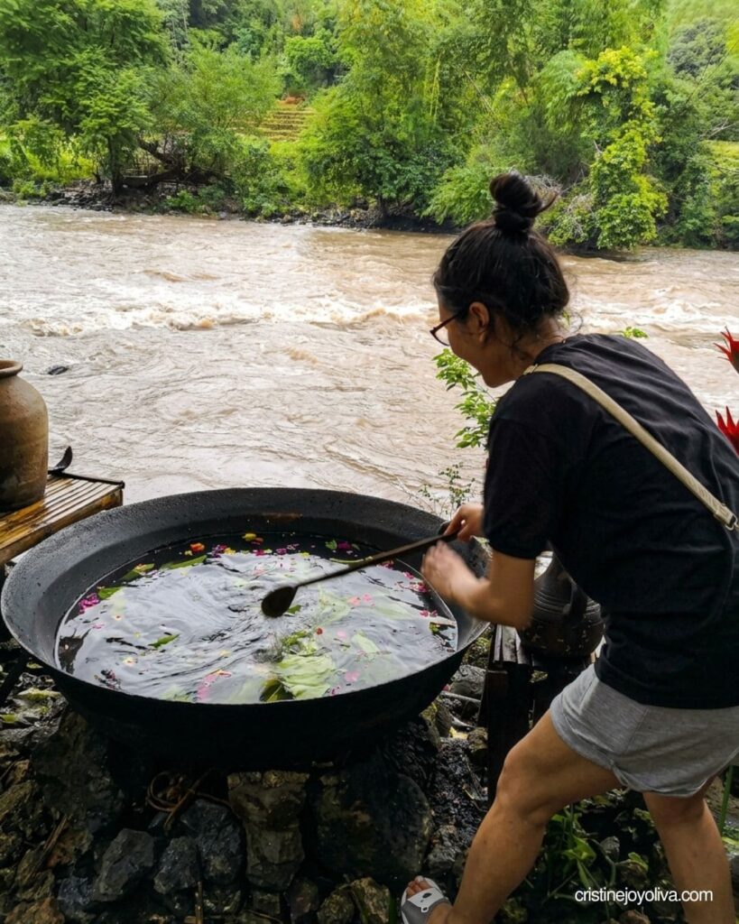 Stirring a kawa hot bath filled with flowers and leaves at Calawag Mountain Resort
