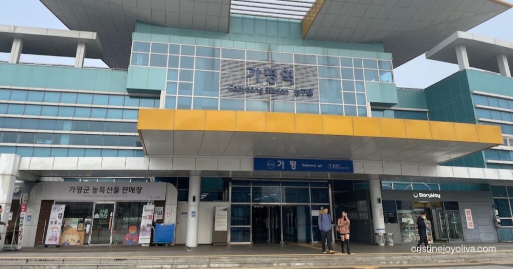 Exterior view of Gapyeong Station in South Korea, a modern Korail railway hub with a glass facade and local specialty shops.