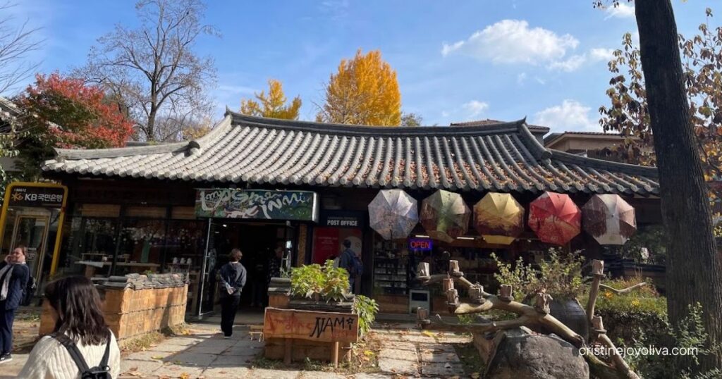Traditional Korean-style building with a tiled roof and colorful umbrella decorations on Nami Island in autumn