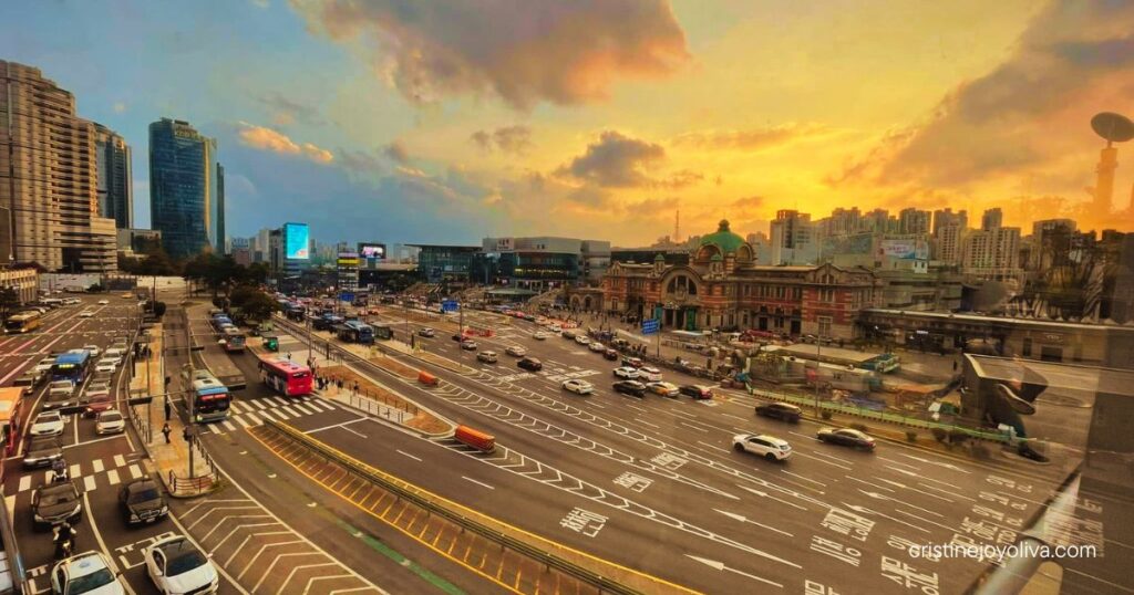 Sunset view from Seoullo 7017 of a wide Seoul street with buses and cars, the old Seoul Station building, and city skyline