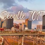 View of Seoul Station railway tracks from Seoullo 7017 with city skyscrapers and autumn trees under a cloudy dusk sky
