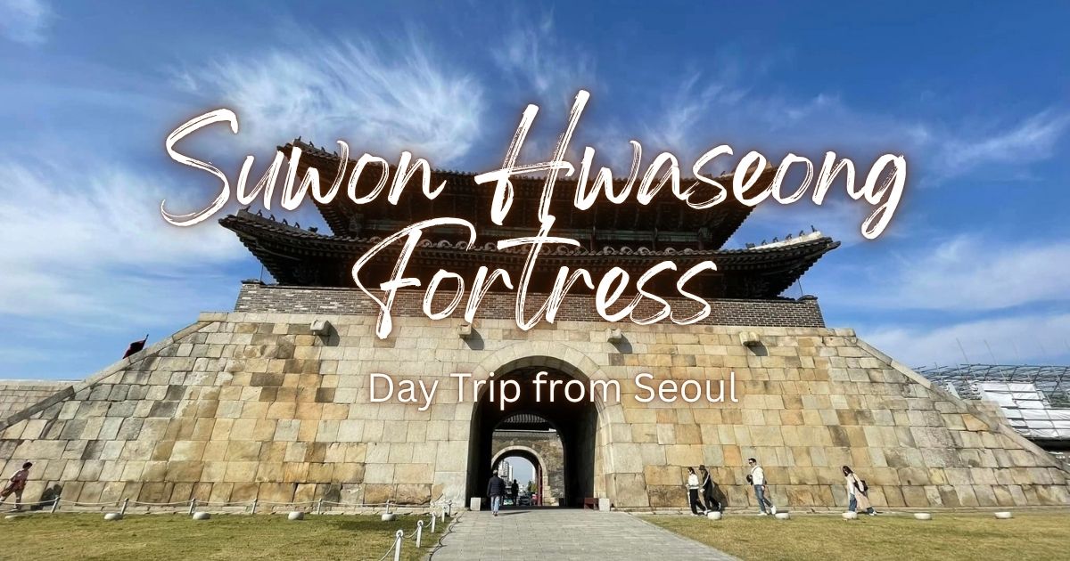 Suwon Hwaseong Fortress day trip from Seoul: stone gate with tiled-roof pavilion under a blue sky with wispy clouds